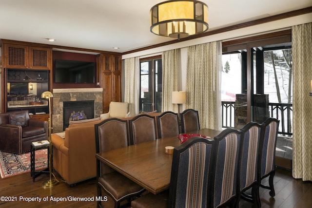 dining space featuring a fireplace, dark wood-type flooring, and ornamental molding