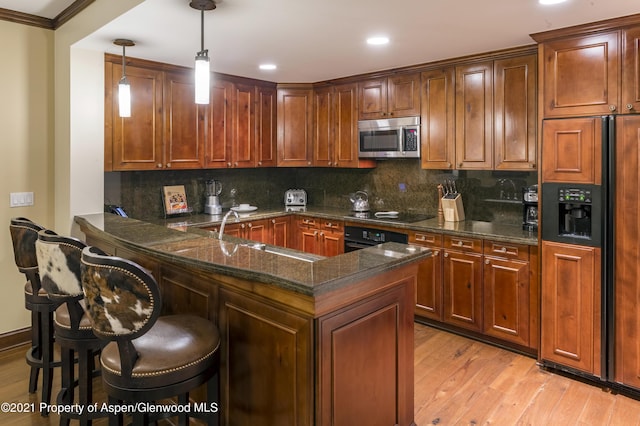 kitchen with sink, hanging light fixtures, kitchen peninsula, a breakfast bar, and black appliances