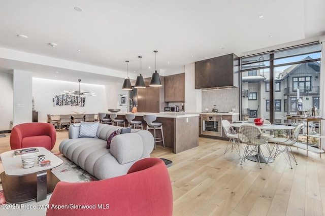 living room featuring a notable chandelier, light hardwood / wood-style floors, and beverage cooler