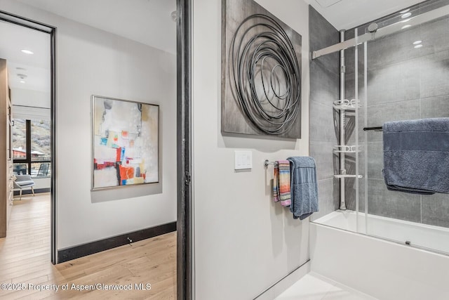 bathroom featuring hardwood / wood-style flooring and enclosed tub / shower combo