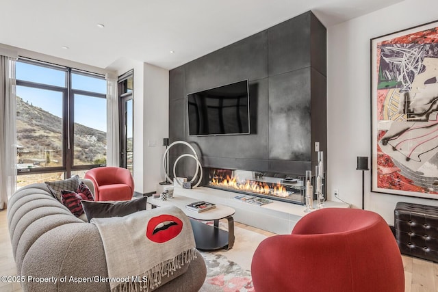 living room with expansive windows, a large fireplace, and light hardwood / wood-style floors