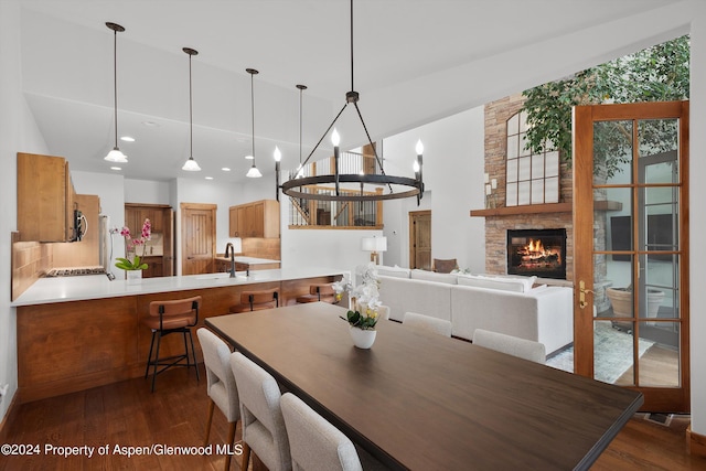 dining space featuring a stone fireplace, dark hardwood / wood-style flooring, vaulted ceiling, and sink