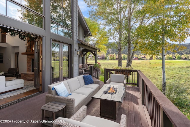 wooden terrace with a yard, french doors, and an outdoor living space with a fire pit