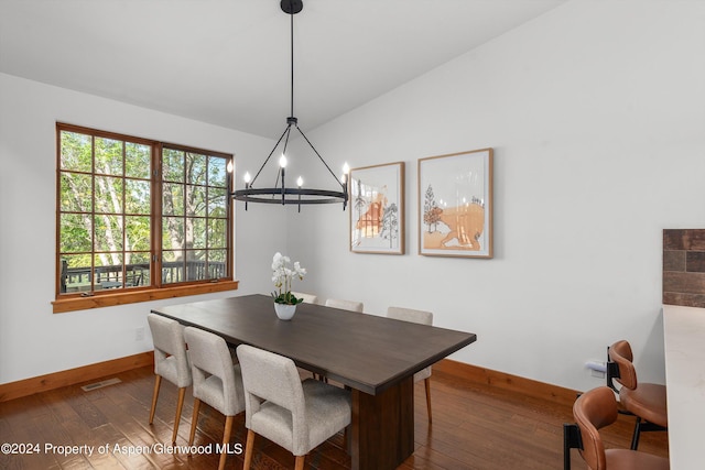 dining area featuring dark hardwood / wood-style floors, an inviting chandelier, and vaulted ceiling