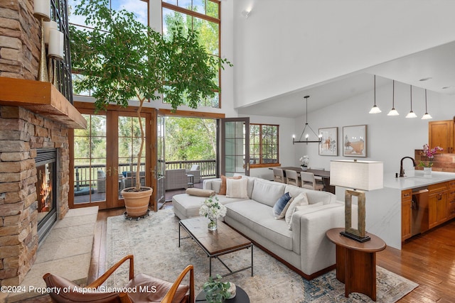 living room with sink, a towering ceiling, light wood-type flooring, and a fireplace