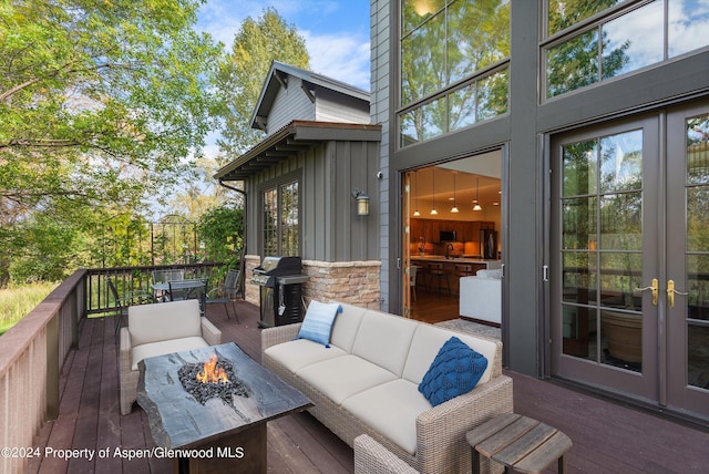 deck featuring french doors, area for grilling, and an outdoor living space with a fire pit