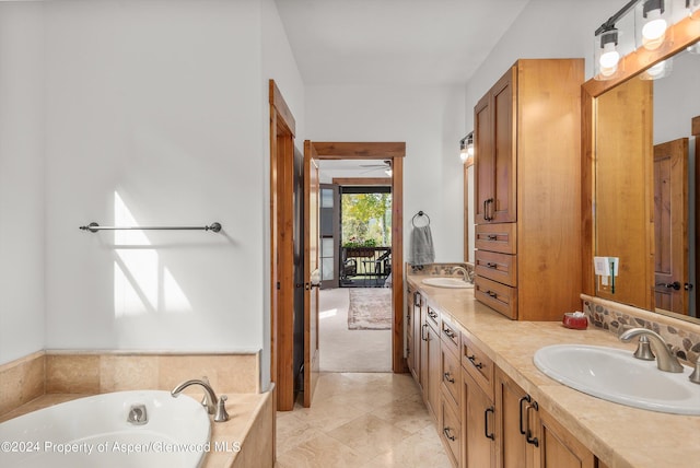 bathroom with tile patterned floors, vanity, and a relaxing tiled tub