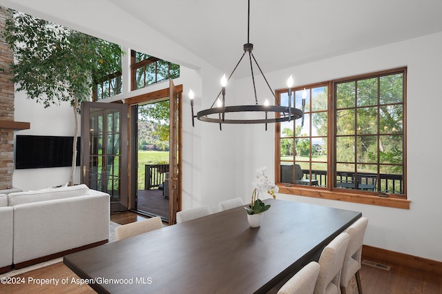 dining space with a chandelier, vaulted ceiling, and wood-type flooring