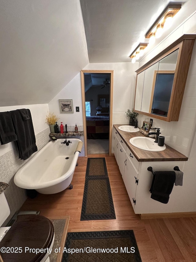595 Colorado St, Craig, CO 81625 - full bath featuring wood finished floors, a freestanding bath, lofted ceiling, double vanity, and tasteful backsplash