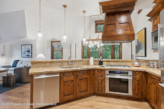 kitchen featuring premium range hood, sink, light hardwood / wood-style flooring, kitchen peninsula, and stainless steel appliances