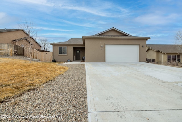 ranch-style house with driveway, an attached garage, fence, and stucco siding