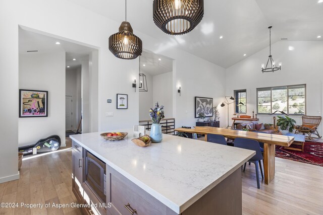 kitchen featuring stainless steel microwave, a center island, pendant lighting, and light hardwood / wood-style flooring