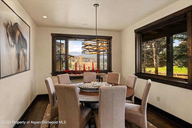 dining area featuring dark wood-type flooring, a wealth of natural light, and an inviting chandelier