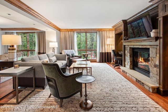 living room featuring hardwood / wood-style floors, a stone fireplace, and crown molding