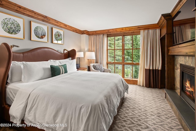 carpeted bedroom with a fireplace and crown molding