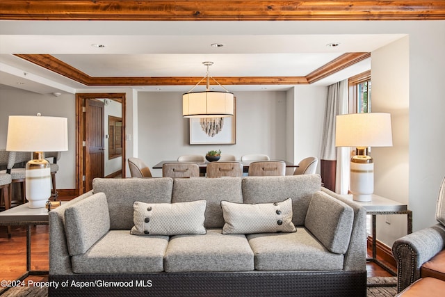 living room with hardwood / wood-style flooring, a raised ceiling, and ornamental molding