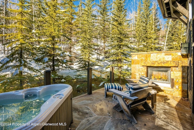 view of patio featuring an outdoor stone fireplace and a hot tub