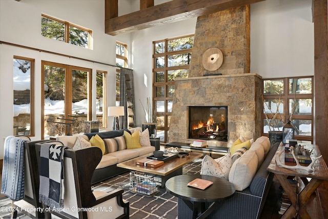 living room with beamed ceiling, a towering ceiling, a wealth of natural light, and a tiled fireplace