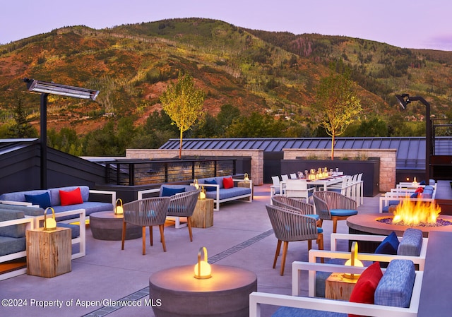 patio terrace at dusk with a mountain view and an outdoor living space with a fire pit