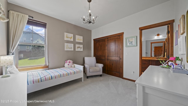 bedroom featuring connected bathroom, a chandelier, and light carpet