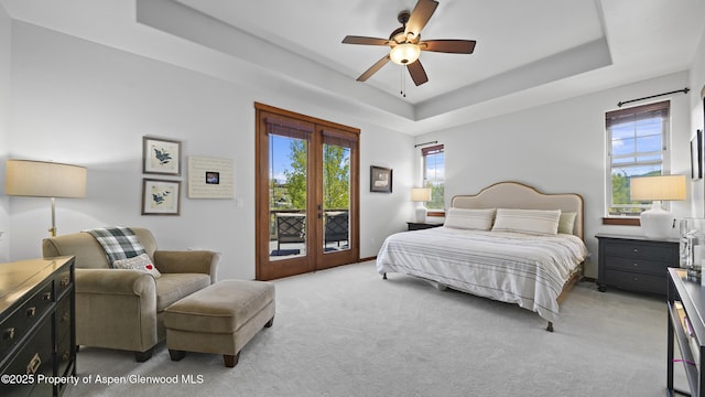 bedroom featuring access to exterior, a raised ceiling, ceiling fan, and french doors