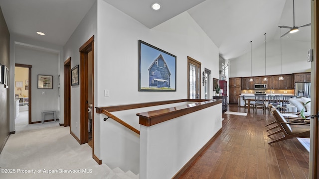 corridor featuring high vaulted ceiling and light hardwood / wood-style flooring