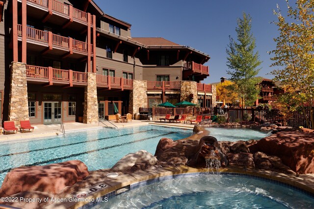 view of swimming pool with french doors and pool water feature