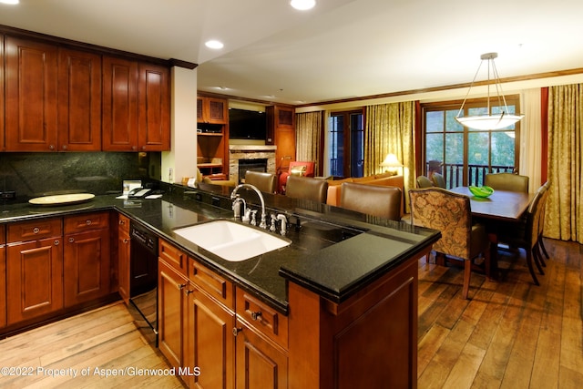 kitchen with a fireplace, sink, light hardwood / wood-style floors, and black dishwasher