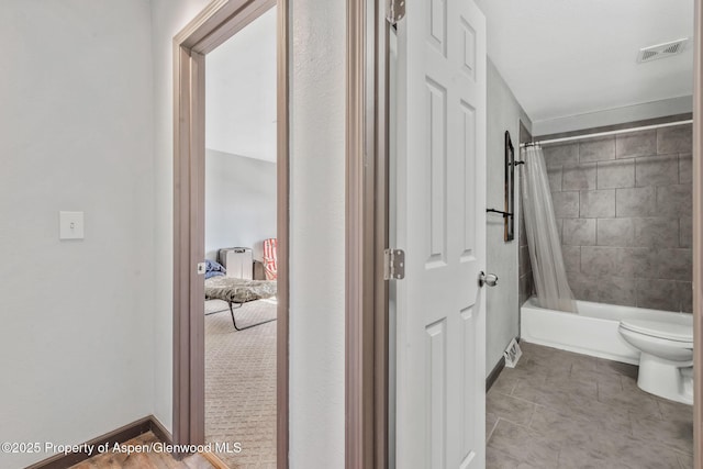 bathroom with shower / bath combination with curtain, toilet, visible vents, and baseboards