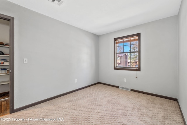 spare room with baseboards, visible vents, and carpet