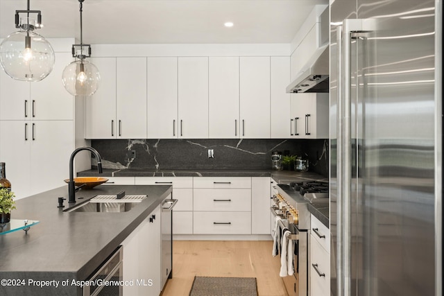 kitchen featuring white cabinets, sink, hanging light fixtures, premium appliances, and beverage cooler