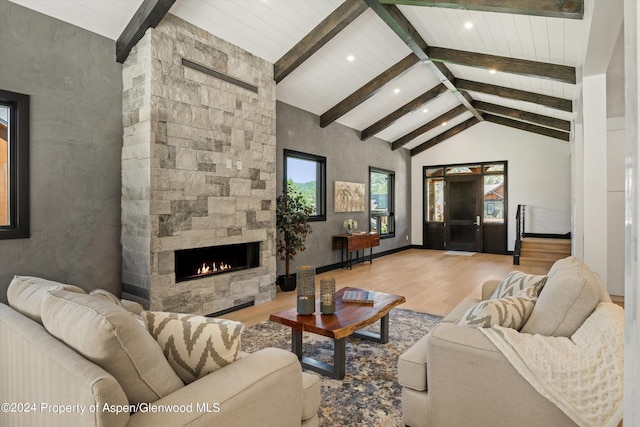 living room featuring a fireplace, beamed ceiling, high vaulted ceiling, and light wood-type flooring