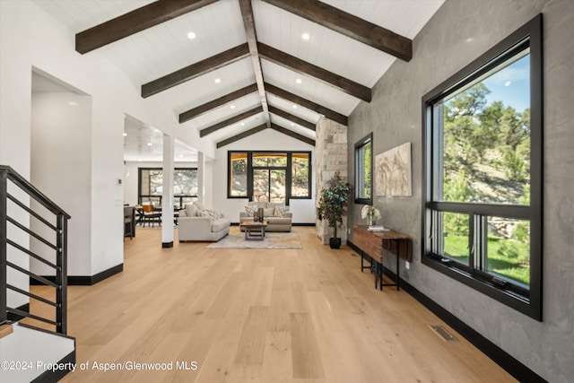 interior space featuring beam ceiling, light wood-type flooring, and high vaulted ceiling