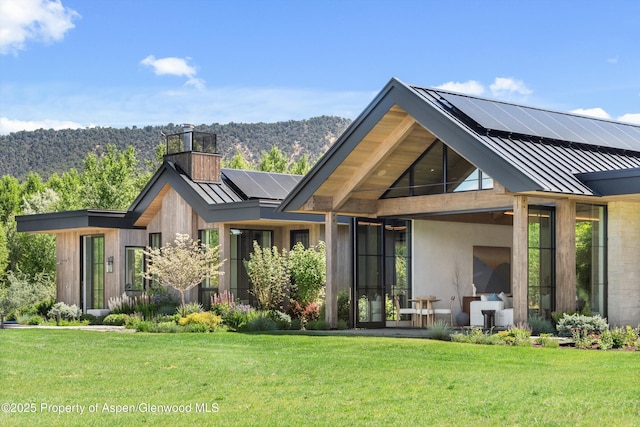 33 St Finnbar Farm Rd, Carbondale, CO 81623 - back of house featuring a standing seam roof, roof mounted solar panels, a metal roof, and a lawn