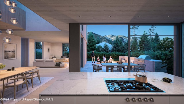 kitchen featuring light stone countertops, black gas cooktop, a mountain view, plenty of natural light, and white cabinets