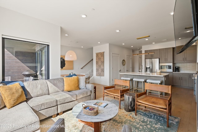 living area with stairs, recessed lighting, and light wood-style floors