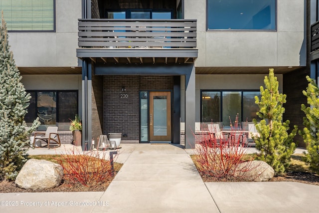 exterior space featuring stucco siding, a patio, brick siding, and a balcony