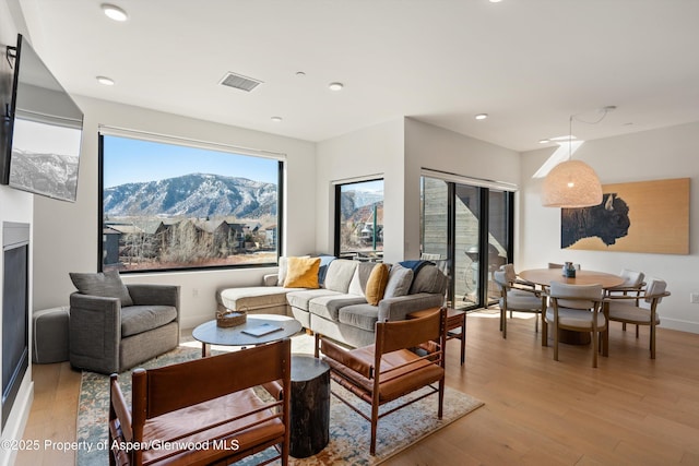 living room with recessed lighting, visible vents, baseboards, and light wood finished floors