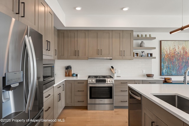 kitchen featuring tasteful backsplash, stainless steel appliances, light countertops, and a sink