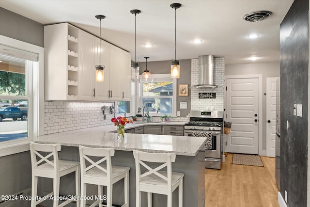 341 Park Dr, Glenwood Springs, CO 81601 - kitchen featuring stainless steel gas range oven, open shelves, a peninsula, light stone countertops, and wall chimney exhaust hood