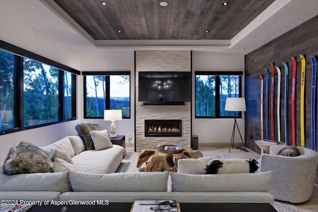 living room featuring wood ceiling, a fireplace, and a tray ceiling