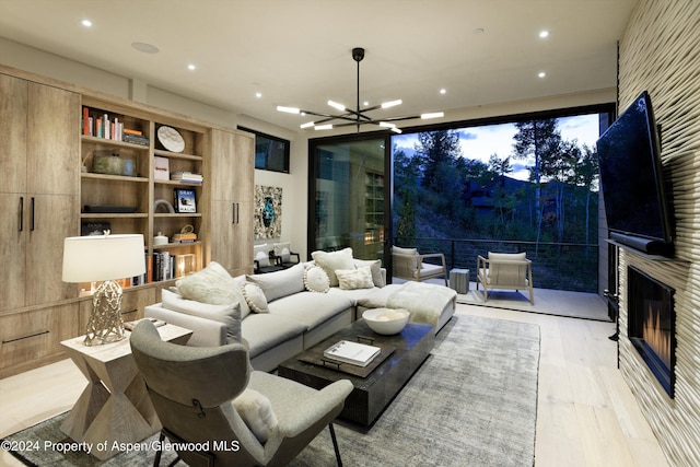 living room featuring a large fireplace, light hardwood / wood-style floors, and an inviting chandelier