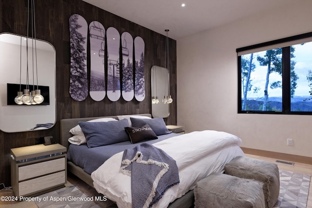 bedroom featuring hardwood / wood-style flooring and wood walls