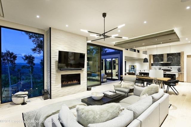 living room with a large fireplace, light hardwood / wood-style flooring, and an inviting chandelier