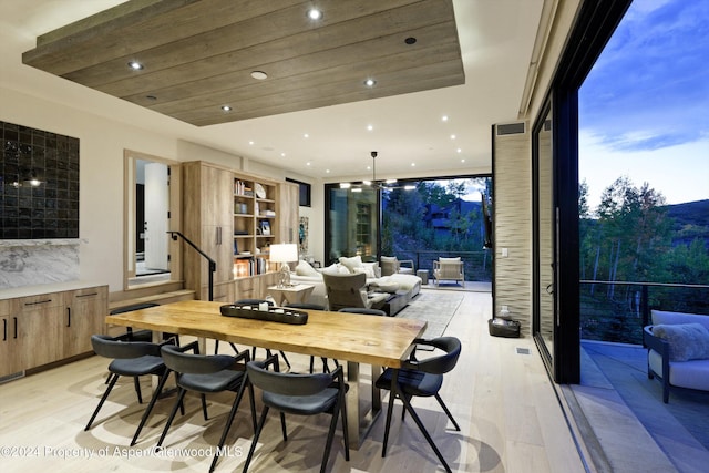 dining room featuring light wood-type flooring and wood ceiling