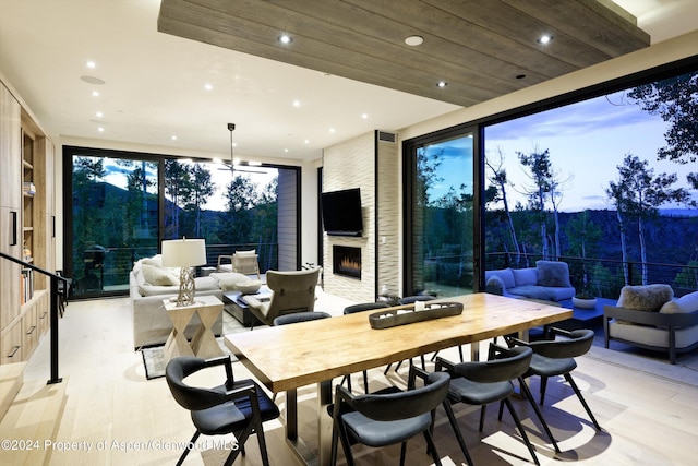 dining area with light hardwood / wood-style floors, wooden ceiling, and a fireplace