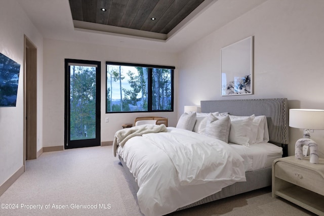 carpeted bedroom featuring a raised ceiling and wood ceiling