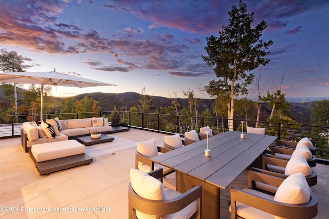 patio terrace at dusk featuring a mountain view and an outdoor hangout area