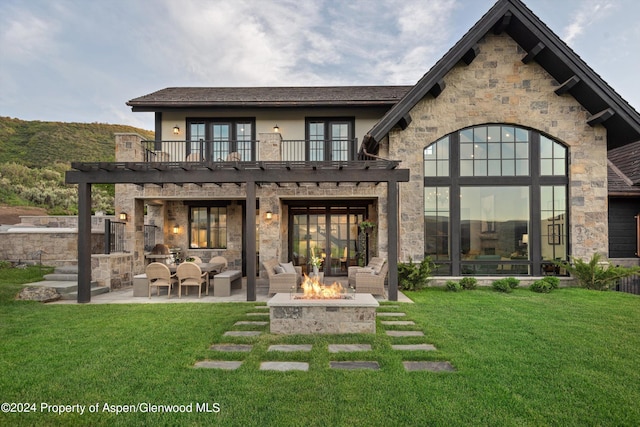 rear view of property featuring french doors, a yard, a balcony, and a patio area