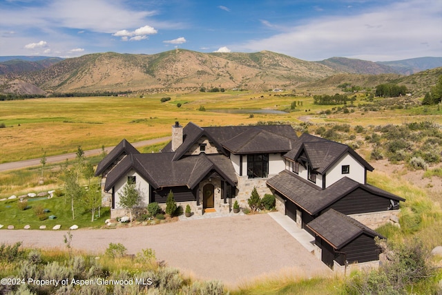 view of front of property with a chimney, a mountain view, stone siding, a rural view, and driveway